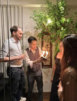 Linus performing a card trick for a small dinner group