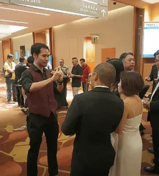 Linus performing close-up magic for guests at a corporate event